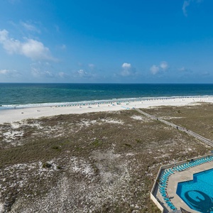 Stunning view of the beach and turquoise waters, featuring a pool area and lounge chairs for relaxation
