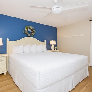 Cozy king suite featuring a blue accent wall, TV, and soft lighting from bedside lamps