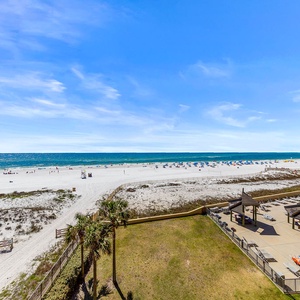 Pristine beach with white sand, colorful umbrellas, and a pool area featuring shaded seating and lounge chairs