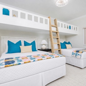 Experience comfort in this guest bedroom with two queen beds, vibrant decor, and two fun lofted twin beds above