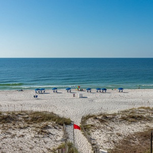 Enjoy breathtaking beachfront views with vibrant blue umbrellas and soft sand, perfect for relaxation and fun