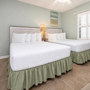 Rest in this bright guest bedroom featuring two comfortable double beds and soft linens