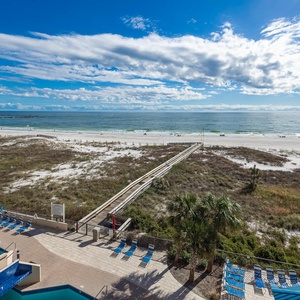 Gaze at the inviting pool area, with lounge chairs and easy access to the beach just steps away from your retreat