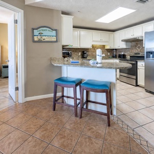Gather around the breakfast bar with teal stools, enjoying easy access to the kitchen and a cozy master bedroom view