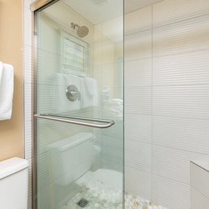 Textured tile walls and a pebble floor enhance your refreshing shower after a day on the coast