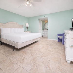 The master bedroom features a light teal accent wall, a comfortable king bed, and a flat-screen TV, perfect for relaxation