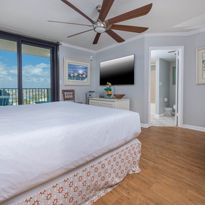 The master bedroom features a king bed, modern decor, and large windows offering a glimpse of the balcony and views beyond