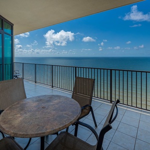 Savor the stunning beach views while sharing laughs with loved ones around the table on your balcony