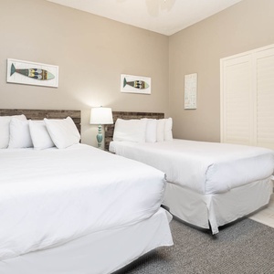 Unwind in this cozy guest bedroom featuring two double beds, soft linens, and beach-themed decor for a relaxing stay