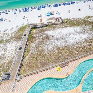 Kids splash and float on colorful tubes in the curving pool beside your beachfront boardwalk access
