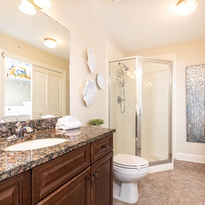 The extra bath features a granite countertop, stylish decor, walk-in glass shower, and laundry area with a washer and dryer