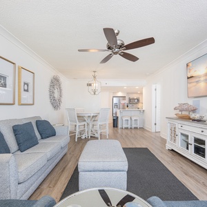 Living area features a light gray sofa queen sleeper, a dining table, and a view of the kitchen with bar seating