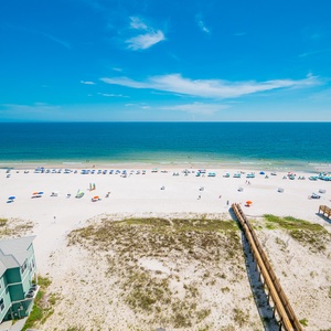 Enjoy the vibrant beach scene with colorful umbrellas and sunbathers along the inviting shoreline just steps away