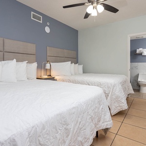 Relax in this spacious guest room featuring two queen beds, soft linens, and a ceiling fan for added comfort