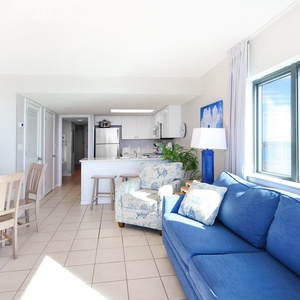 Relax in the airy living space with a blue sofa with queen sleeper, dining area, and panoramic beach views