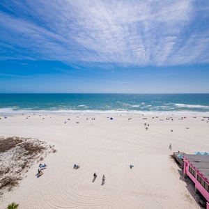 Bright blue sky stretches above the shore where gentle waves lap and laughter drifts on the breeze