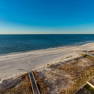 A serene beachfront view showcases white sand and gentle waves, inviting relaxation and enjoyment of the coastal atmosphere