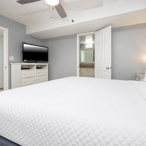 Bright and inviting bedroom featuring a cozy king bed, flat-screen TV, and an ensuite bathroom for added convenience