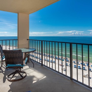 Enjoy breathtaking views from the balcony, featuring a table and chairs overlooking the serene beach and vibrant umbrellas