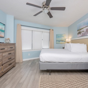 Relax in this serene master suite featuring a cozy king bed, modern decor, and a flat-screen TV for your entertainment