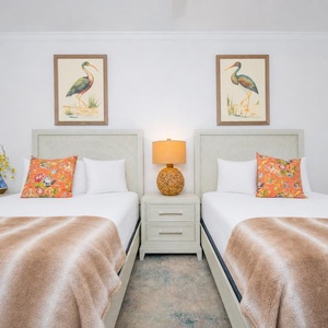 Guest suite with two queen beds offers restful comfort with floral pillows and soft neutral throws