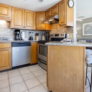 Kitchen featuring wooden cabinetry, granite countertops, and stainless appliances, with a view of the beachfront balcony