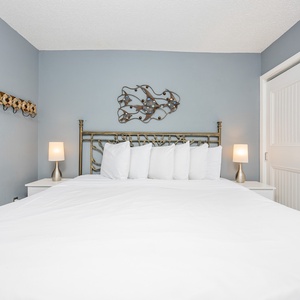 This bedroom features a stylish metal headboard, soft white bedding, and cozy lamps, creating a serene retreat