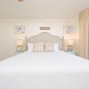 Cozy master bedroom featuring a king bed with decorative pillows, bedside lamps, and a view through the large window