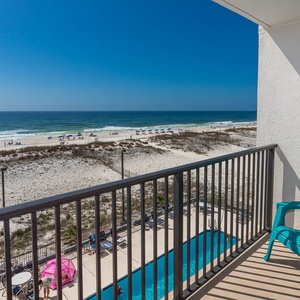 Enjoy a stunning beachfront view from the balcony, complete with vibrant teal chairs and a relaxing atmosphere