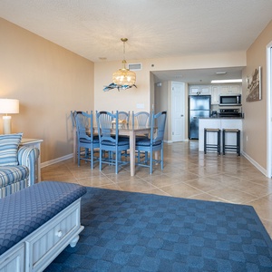 Living area features a striped sofa with queen sleeper, decorative accents, and a dining table with blue chairs