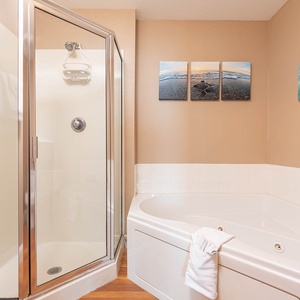 The bathroom features a relaxing whirlpool tub, a separate shower, and soothing artwork that enhances the tranquil atmosphere