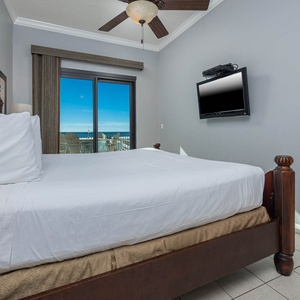 Unwind in the master bedroom featuring a king bed, a TV, and sliding doors leading to a beautiful beach view