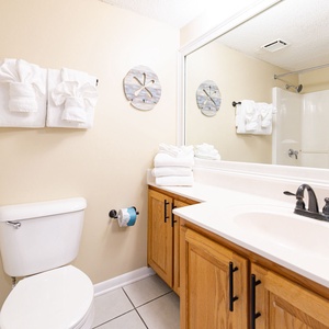 Towels arranged like seashells add a playful touch to the guest bath's soothing decor and shower area