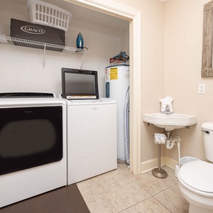 This practical laundry area features a washer, dryer, and a convenient half bath for your cleaning needs during your stay