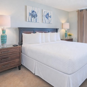 Relax in this serene master bedroom, featuring a king bed, stylish decor, and beachfront balcony access