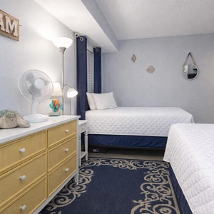 Inviting guest room features two double beds, a wall-mounted TV, and beach-themed decor for a relaxing stay
