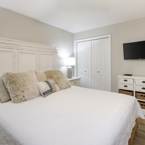 Chic guest bedroom featuring a king bed with plush pillows, a mounted TV, and stylish storage options for a relaxing retreat