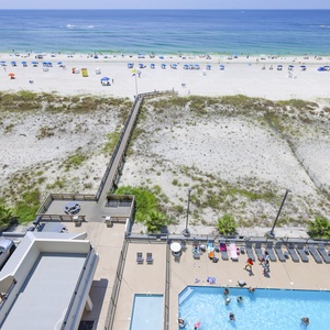 This view showcases a vibrant beachfront with a sparkling pool area, inviting guests to relax and enjoy their stay