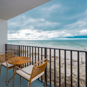 Enjoy a cozy seating area on the balcony with a view of the beach, perfect for relaxing and taking in the scenery