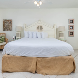 Relax in this spacious master bedroom featuring a large king bed, coastal decor, and beachfront balcony access