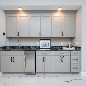 Enjoy preparing snacks and drinks at this wet bar area, featuring stylish cabinetry and elegant countertops