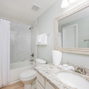 Towel wraps invite you to refresh in the bathroom with a granite countertop and marbled tub surround