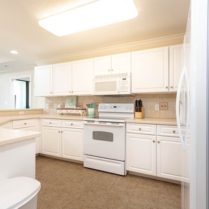 Cook and gather in the spacious kitchen featuring ample counter space, white cabinetry, and white appliances