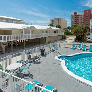 The inviting pool area features a sparkling blue pool surrounded by comfortable lounge chairs, perfect for relaxation and fun