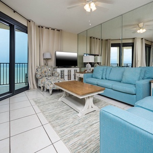 Relax in the airy living room featuring a sofa with queen sleeper, large TV, and stunning beach views