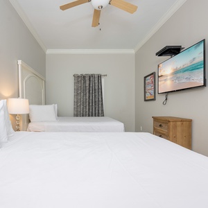Rest in comfort with two queen beds, a mounted TV, and charming decor that invites relaxation after a day of adventure