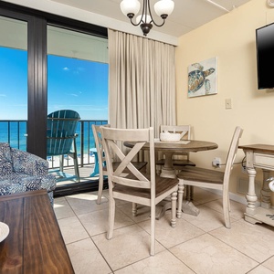 This inviting seating area features a cozy chair and dining table with stunning beachfront views just beyond the glass doors