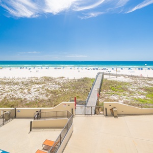 Gentle sun warms your shoulders while you stroll down the wooden path toward soft white sand and shimmering coast