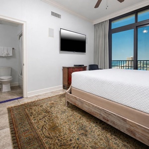 This bedroom features a cozy king bed, a wall-mounted TV, and stunning views through large windows