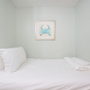 Twin bed featuring white linens and charming nautical decor on soft blue walls